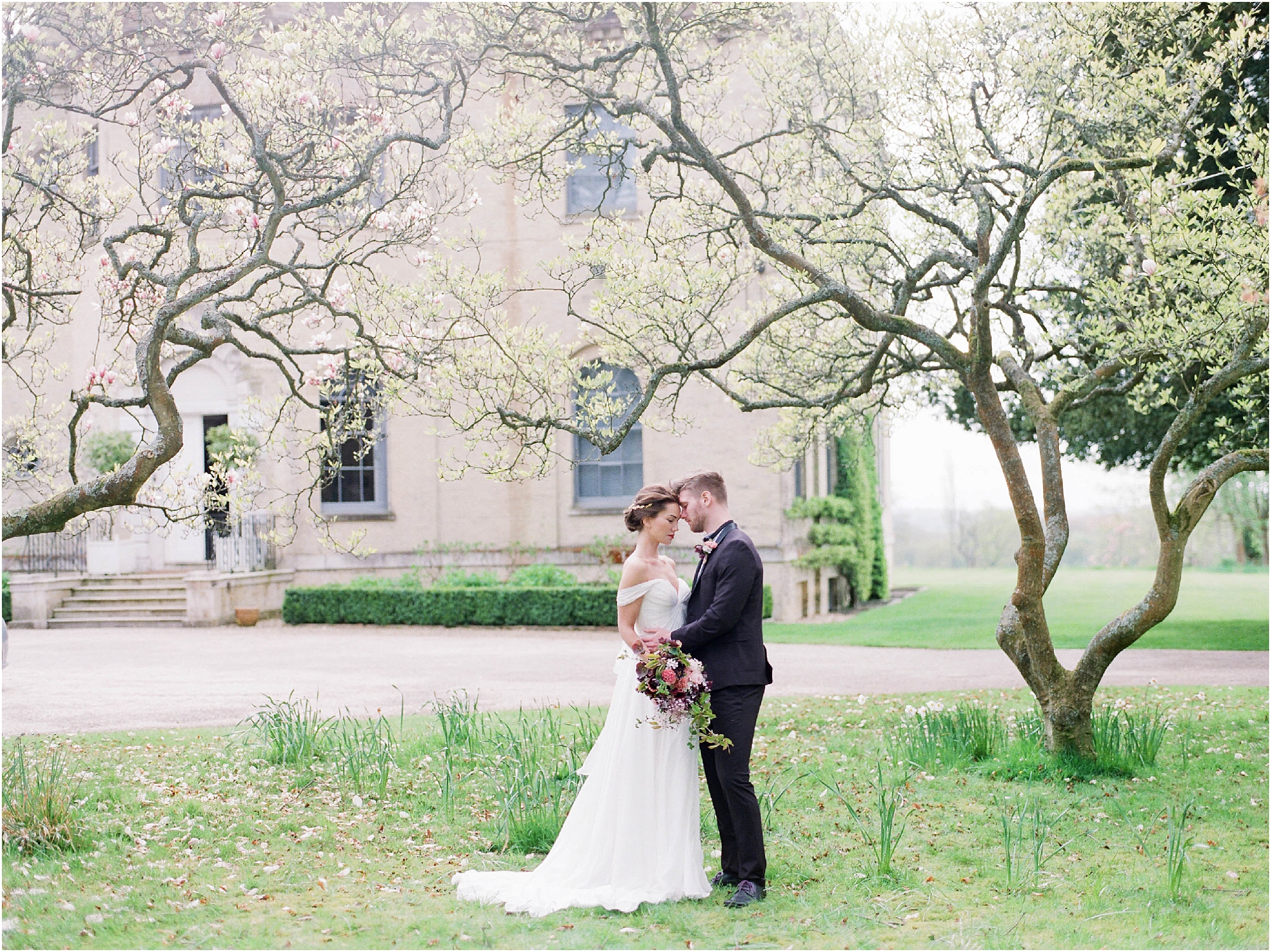 Bride and groom standing under magnolia tree