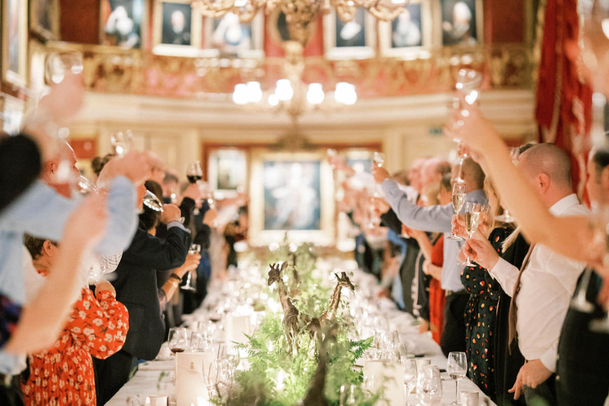wedding guests toasting at Goodwood House wedding venue captured by luxury wedding photographer Camilla Arnhold
